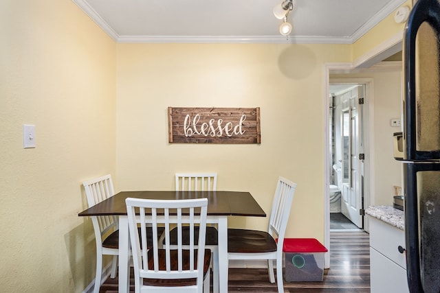 dining area featuring crown molding, track lighting, and dark hardwood / wood-style floors