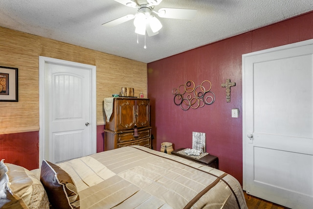 bedroom with ceiling fan, hardwood / wood-style flooring, and a textured ceiling