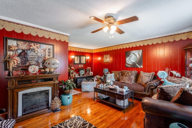 living room with a textured ceiling, ceiling fan, ornamental molding, and hardwood / wood-style flooring