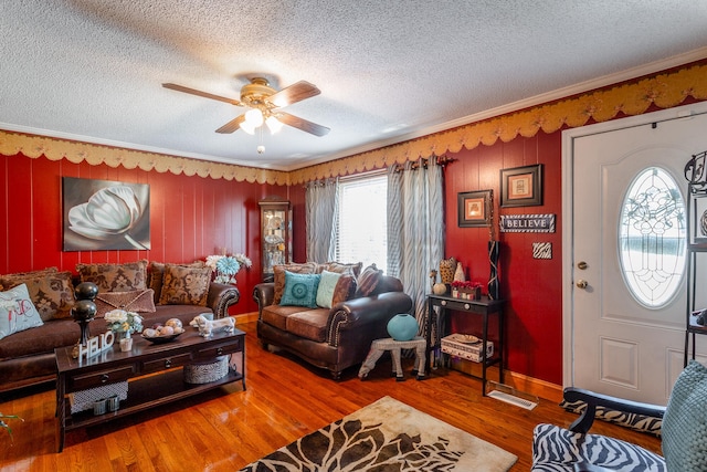 living room with a textured ceiling, ceiling fan, ornamental molding, and hardwood / wood-style flooring