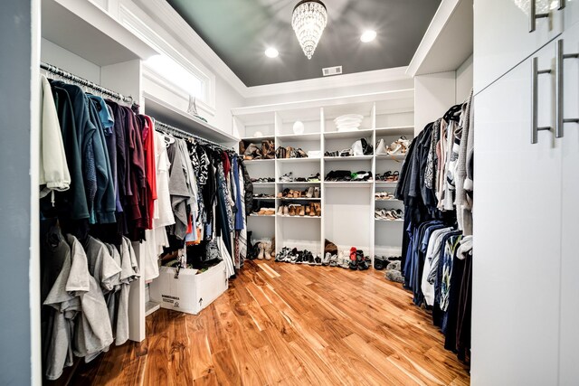 walk in closet with an inviting chandelier and hardwood / wood-style flooring