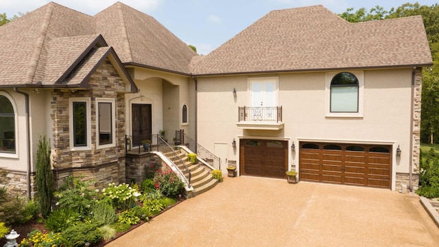 view of front facade with stone siding, a shingled roof, driveway, and stucco siding