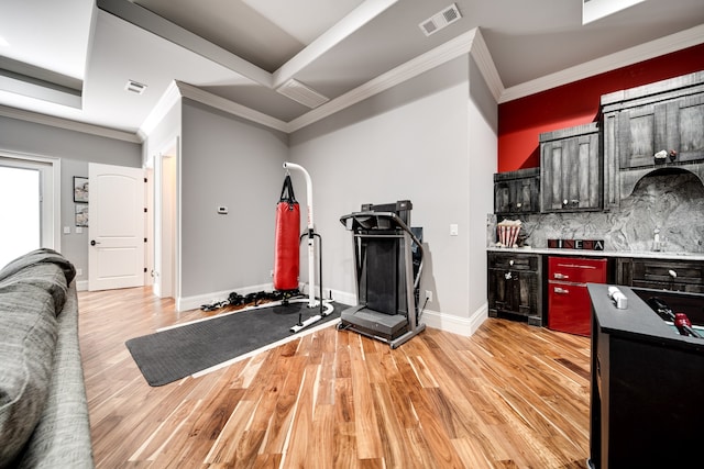 kitchen with light wood-type flooring, crown molding, and decorative backsplash