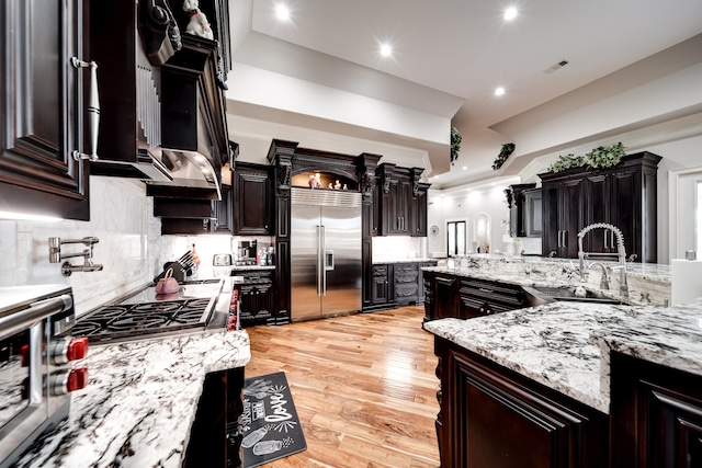 kitchen with sink, tasteful backsplash, appliances with stainless steel finishes, and light wood-type flooring