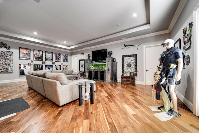 living area featuring light wood-style floors, baseboards, a tray ceiling, and ornamental molding