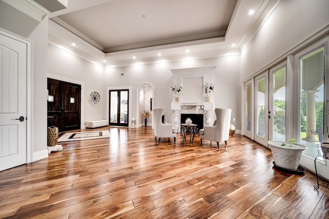 living room with a towering ceiling, light hardwood / wood-style floors, french doors, and a premium fireplace