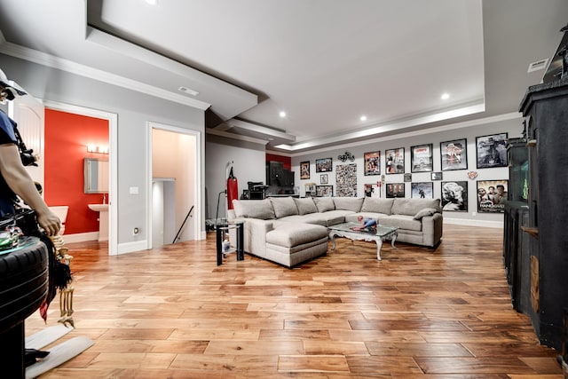 living room with ornamental molding, recessed lighting, a raised ceiling, and light wood-style flooring