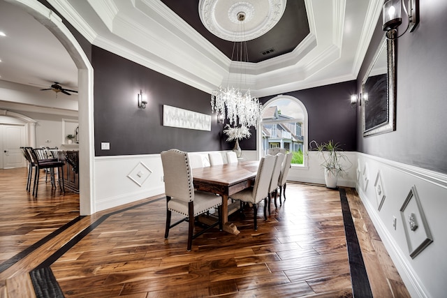 dining room featuring hardwood / wood-style flooring, ceiling fan with notable chandelier, crown molding, and a tray ceiling