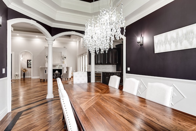 unfurnished dining area with dark hardwood / wood-style flooring, a tray ceiling, decorative columns, a notable chandelier, and crown molding