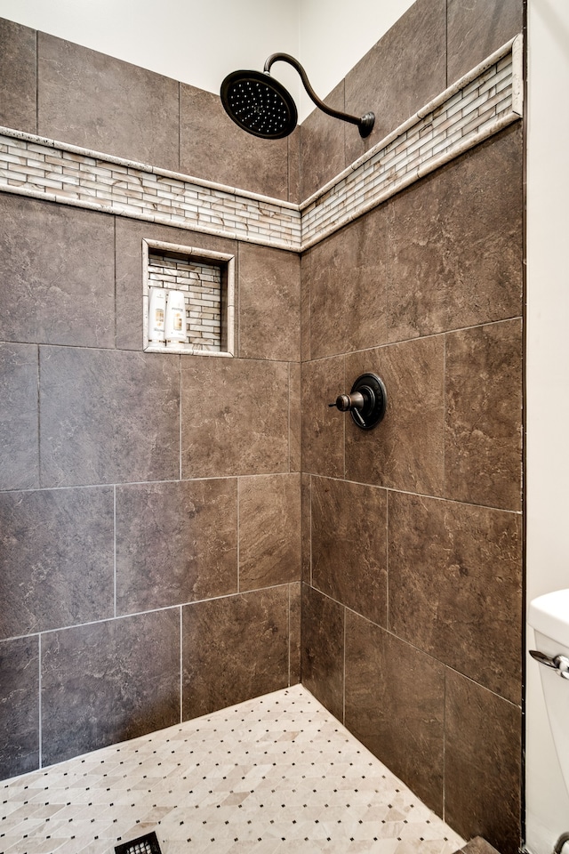 bathroom featuring toilet and a tile shower