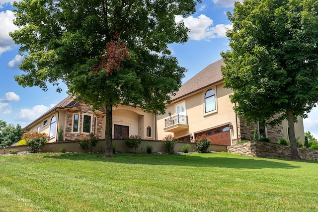 view of front of home with a balcony, a front yard, and a garage