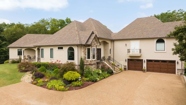 view of front of home with stucco siding, a shingled roof, a garage, stone siding, and driveway