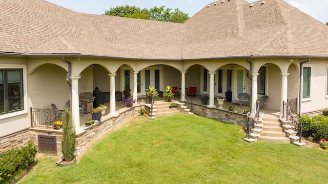 back of property with a shingled roof, a patio, and stucco siding