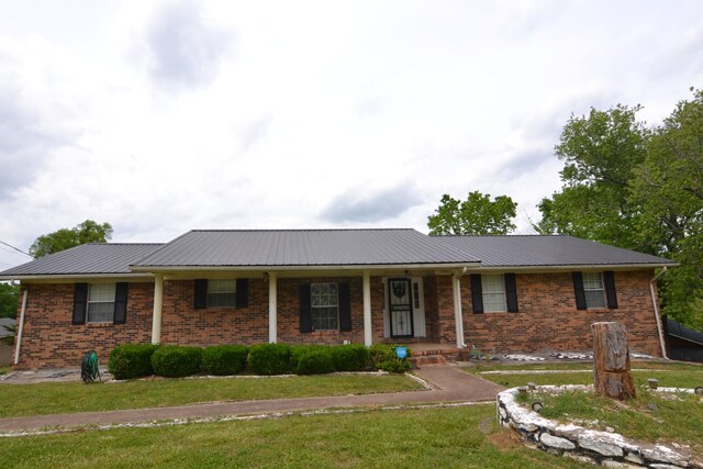 630 Marietta St, Pulaski, TN 38478 - single story home with a front lawn, covered porch, a metal roof, and brick siding