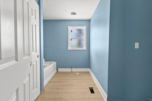 interior space featuring wood-type flooring and a tub to relax in