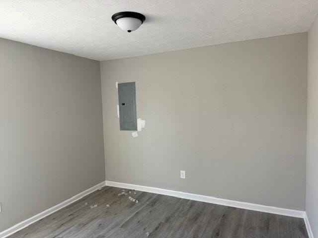 spare room with dark wood-type flooring, electric panel, and a textured ceiling