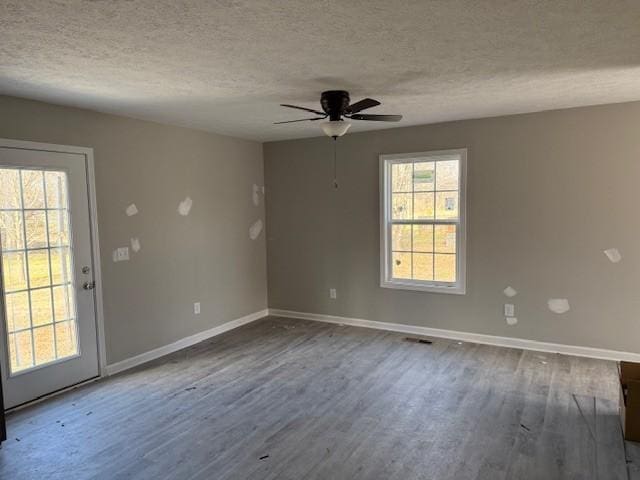 empty room with hardwood / wood-style floors, plenty of natural light, and a textured ceiling