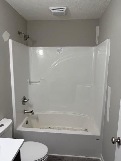 full bathroom featuring vanity, a textured ceiling, toilet, and washtub / shower combination