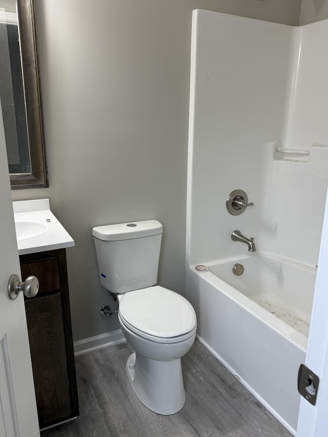 full bathroom featuring shower / tub combination, toilet, wood finished floors, vanity, and baseboards