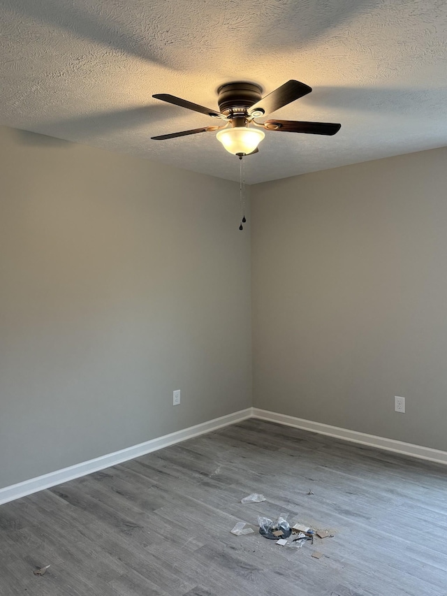 unfurnished room featuring a ceiling fan, a textured ceiling, baseboards, and dark wood-type flooring