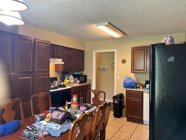 kitchen with a textured ceiling, white appliances, and light tile patterned floors