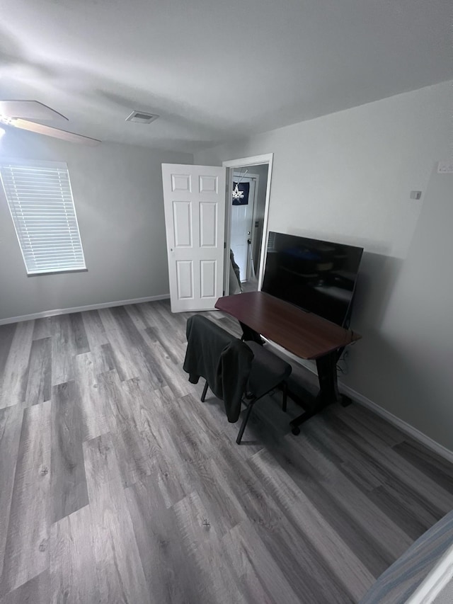 office area featuring a ceiling fan, visible vents, baseboards, and wood finished floors