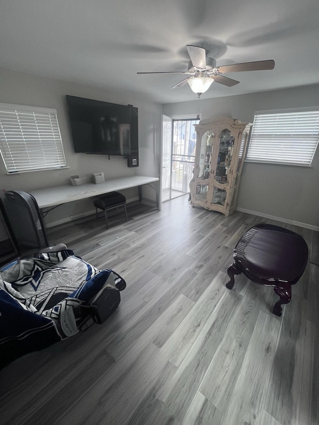 living room with a ceiling fan, baseboards, and wood finished floors