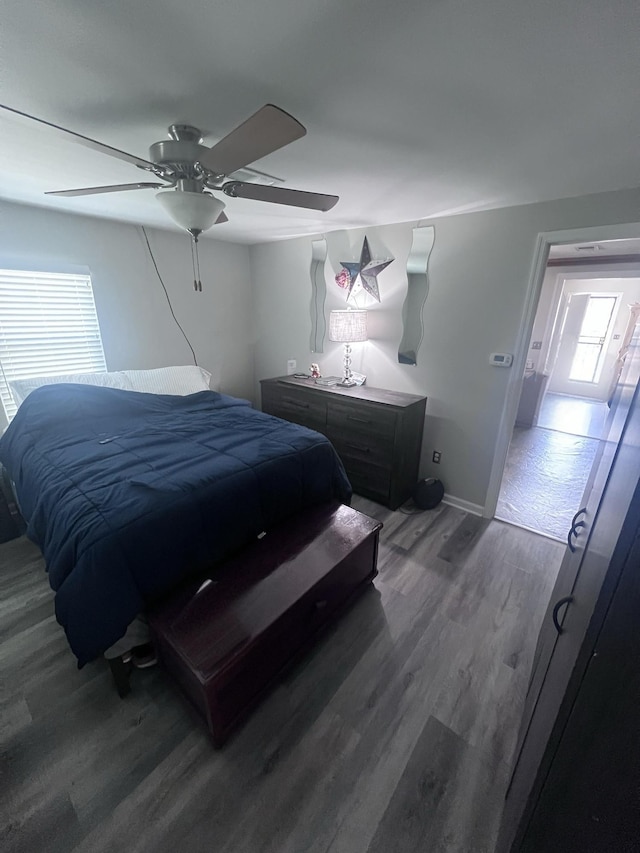 bedroom with ceiling fan, wood finished floors, and baseboards