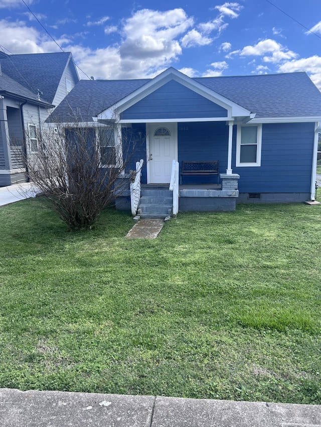 single story home with a porch, roof with shingles, and a front yard