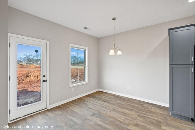 unfurnished dining area with a chandelier and hardwood / wood-style flooring