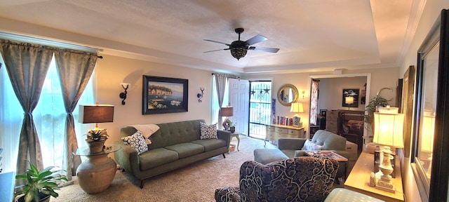 carpeted living room with ceiling fan, a raised ceiling, and ornamental molding