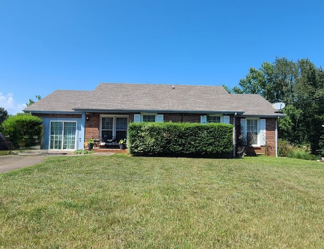 single story home with brick siding, a shingled roof, and a front yard