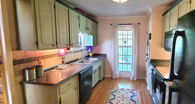 kitchen featuring light hardwood / wood-style flooring, backsplash, green cabinetry, black appliances, and sink