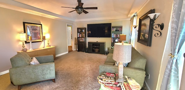 carpeted living room featuring a tray ceiling, ceiling fan, a fireplace, and ornamental molding