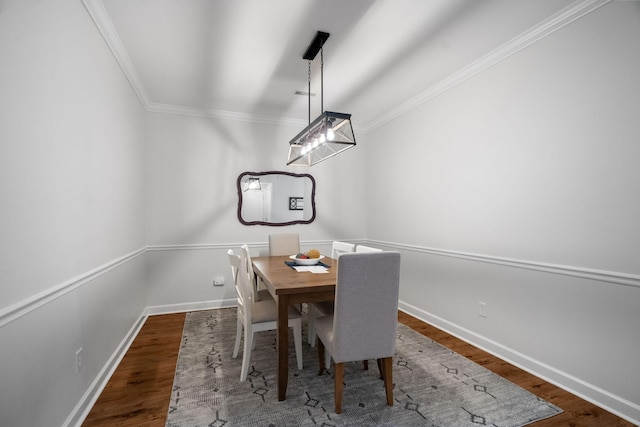 dining room featuring baseboards, wood finished floors, and ornamental molding