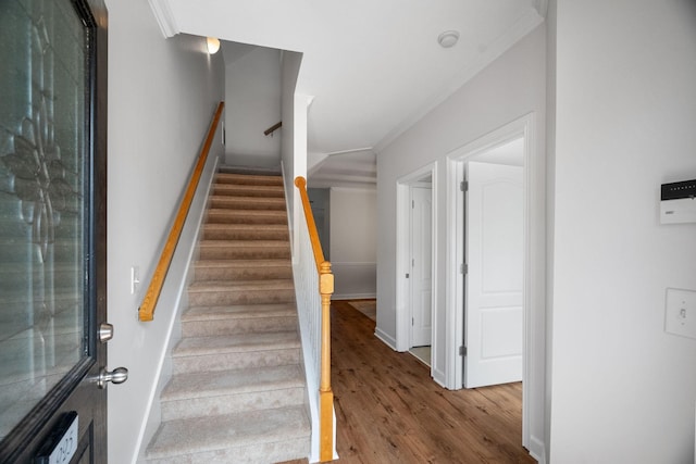 stairs featuring crown molding, baseboards, and wood finished floors