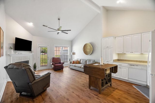 living area featuring a fireplace, visible vents, a ceiling fan, wood finished floors, and high vaulted ceiling