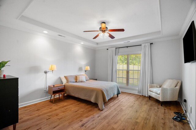 bedroom featuring ceiling fan, light wood-type flooring, and a raised ceiling