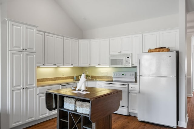 kitchen featuring dark wood finished floors, lofted ceiling, white cabinets, a sink, and white appliances