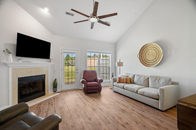 living room featuring visible vents, a ceiling fan, a tile fireplace, wood finished floors, and high vaulted ceiling