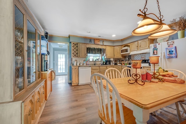 dining area with light hardwood / wood-style floors, crown molding, and sink