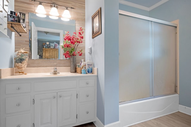 bathroom with wood-type flooring, bath / shower combo with glass door, crown molding, and vanity