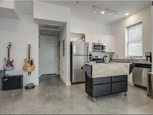 kitchen featuring a center island, stainless steel appliances, track lighting, and white cabinets