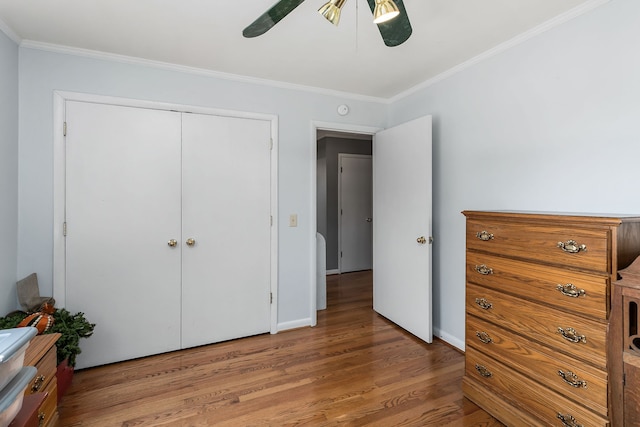 bedroom with a closet, ceiling fan, crown molding, and wood-type flooring