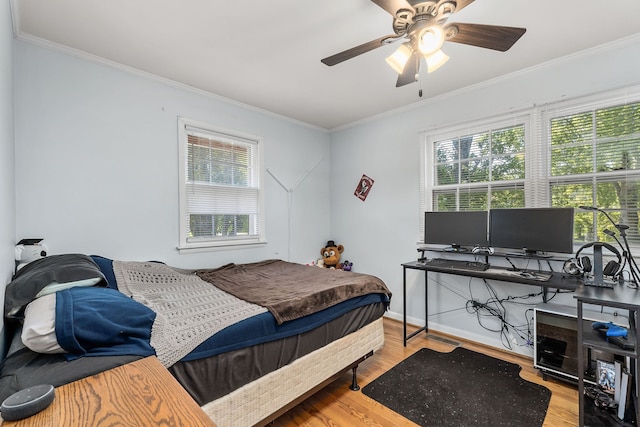 bedroom featuring light wood-type flooring, ornamental molding, and ceiling fan