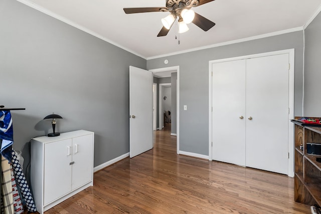 bedroom with light hardwood / wood-style floors, ornamental molding, ceiling fan, and a closet