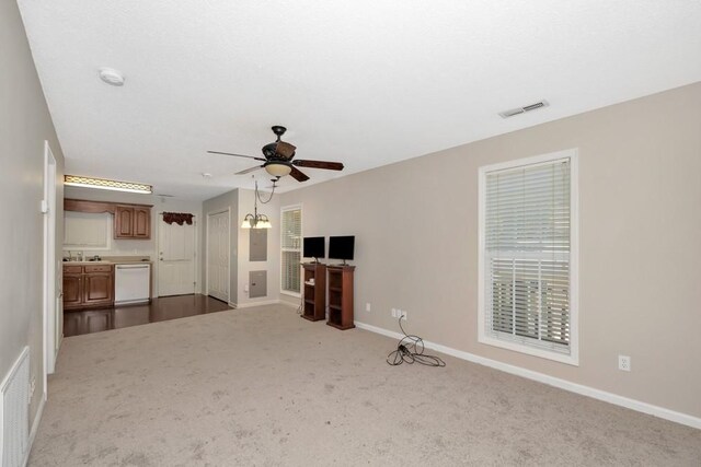 unfurnished living room featuring carpet, sink, and ceiling fan with notable chandelier