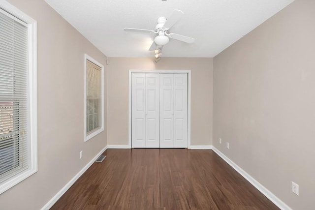 unfurnished bedroom featuring a closet, dark wood finished floors, visible vents, and baseboards