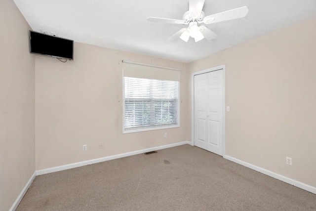 carpeted empty room with a ceiling fan, visible vents, and baseboards