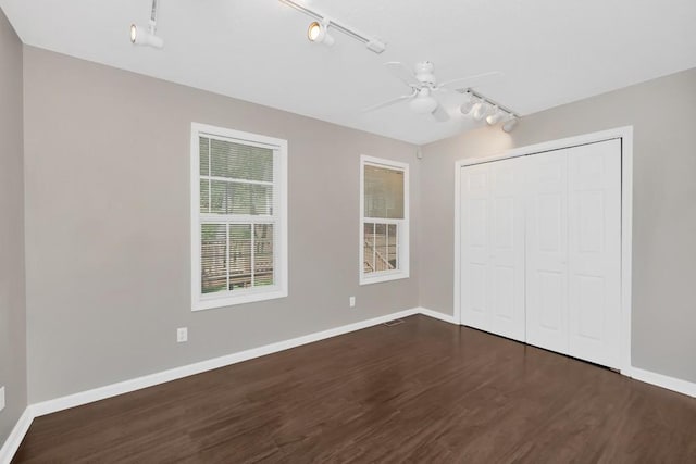 unfurnished bedroom with ceiling fan, a closet, baseboards, and dark wood-style flooring